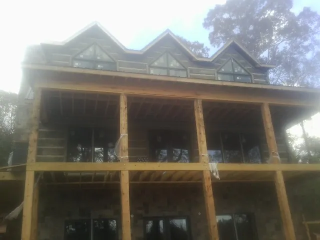 Dormers and porch framing on a large log home under construction — Roof Coating work by our crew in Eglon