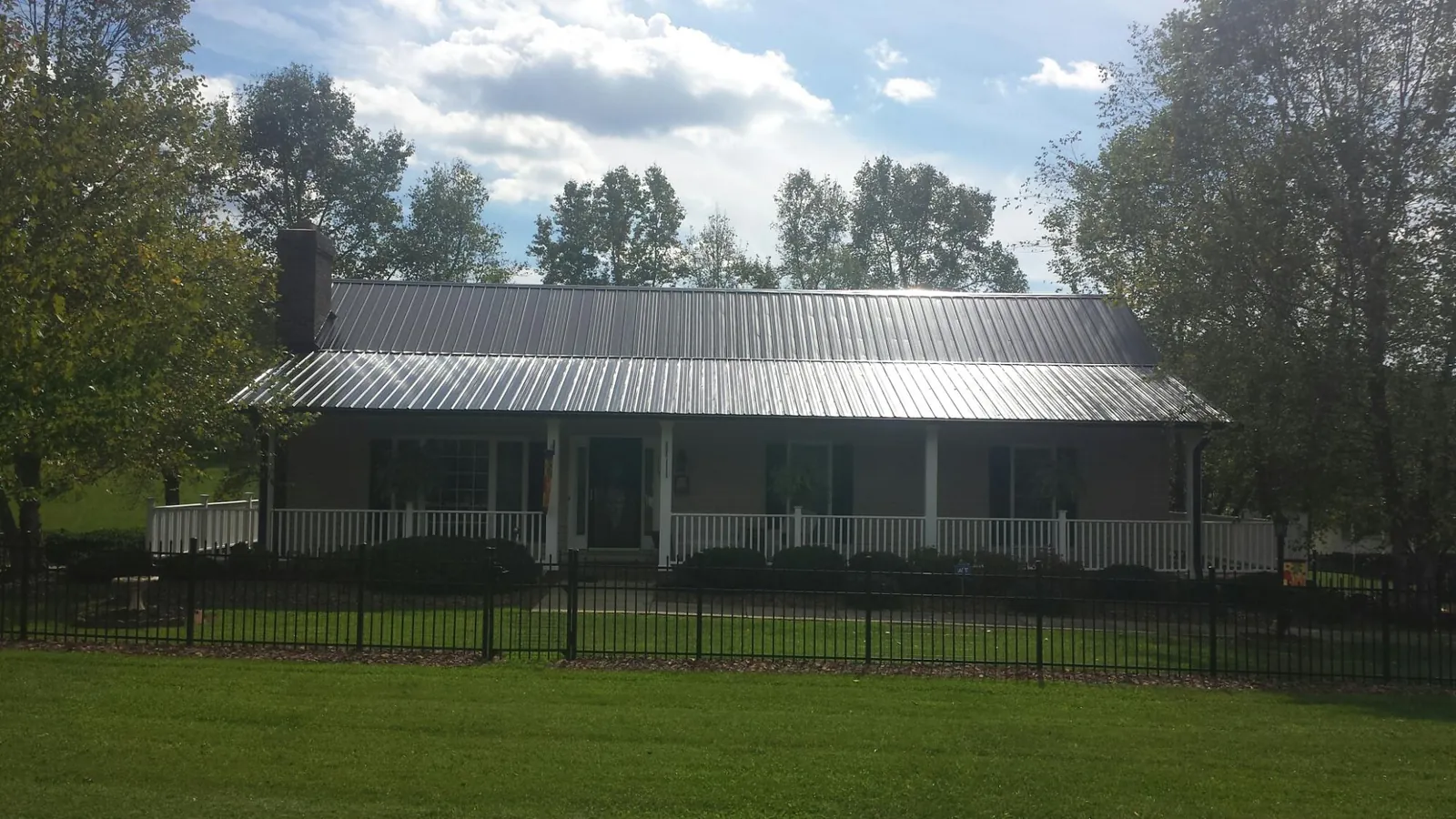 Gray metal roof on a brick ranch with a full width front porch — Gutter Guard Installation work by our crew in Eglon