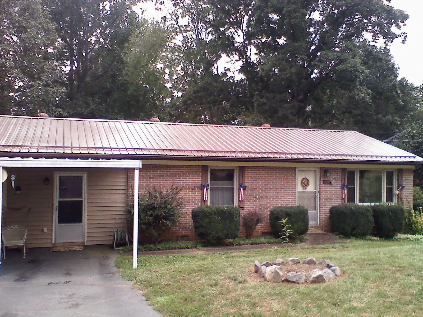 Bronze metal roof and carport on a brick ranch home — Roof Repair work by our crew in Eglon