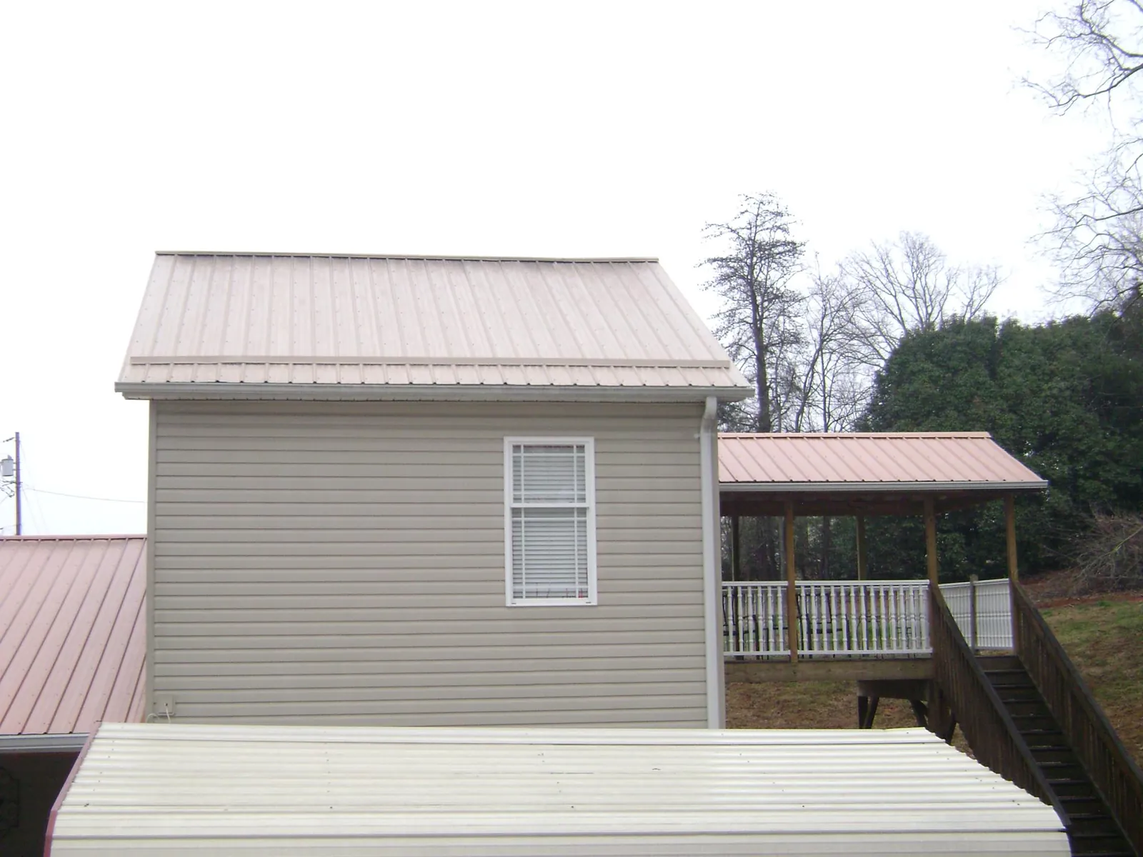 Tan metal roofs on a two story addition and attached porch, from a Roof Replacement job in Eglon