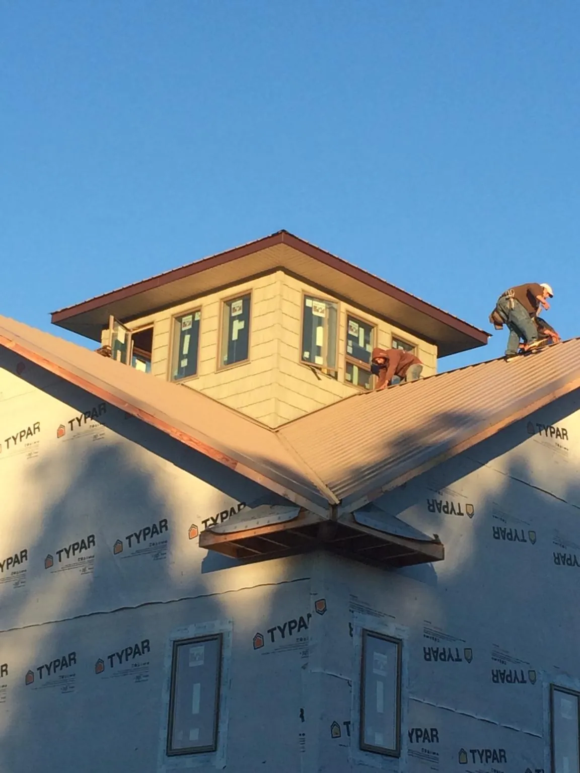 Roofers working around a rooftop cupola on a new metal roof at sunset — Roof Waterproofing in Eglon by Roofing Brothers